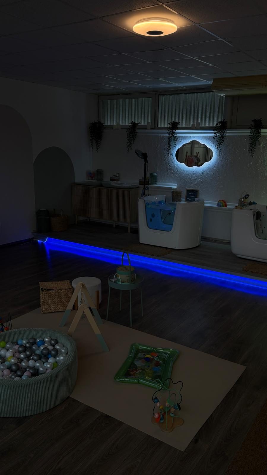 Floating-Becken mit blauem Lichtband, daneben Bällebad und Spielmatte