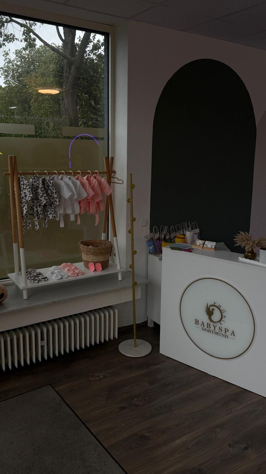 Empfangstresen mit dem Logo Babyspa Phönix Dortmund und Babybademänteln